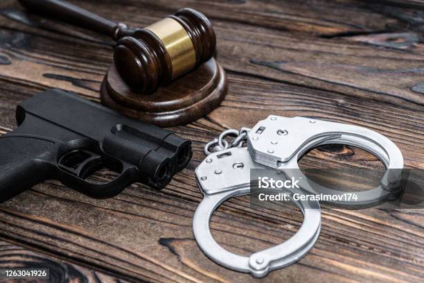 Handcuffs A Judge Hammer A Gun On A Wooden Background Criminal Offense Stock Photo - Download Image Now