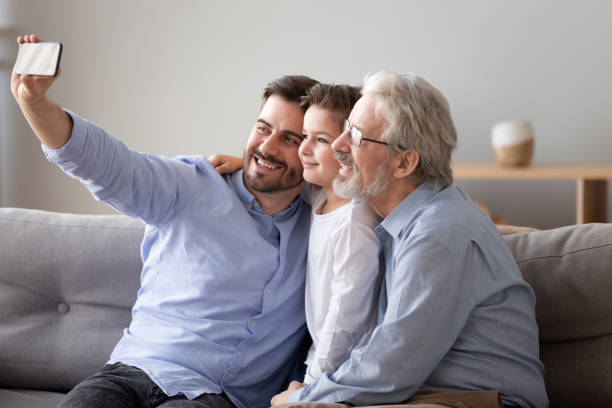 istock Three generations relatives men sitting on couch take selfie photo 1263052908
