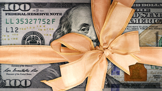 conceptual business and finance image of close up gift wrapped American one hundred dollar bill