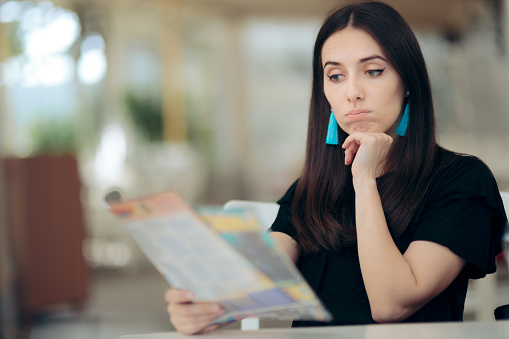 Depressed girl getting stressful information from newspaper article