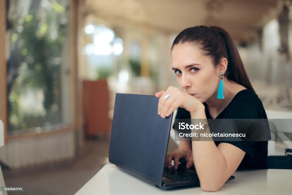 Woman with Laptop Worried About Online Privacy of Personal Data Girl trying to keep her internet data confidential typing password in secret Privacy Stock Photo