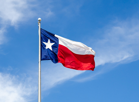 Bandera del estado de Texas ondeando en el ala contra el cielo azul photo