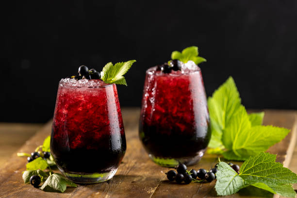 Two glass of cold ice black currant juice or cocktail with ripe stock photo