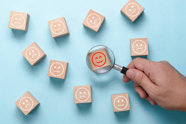 uso de la mano de vidrio de la lupa para encontrar la emoción de la felicidad entre la tristeza y el estado de ánimo regular. satisfacción y evaluación del cliente después del servicio o encuesta de marketing. - infame fotografías e imágenes de stock