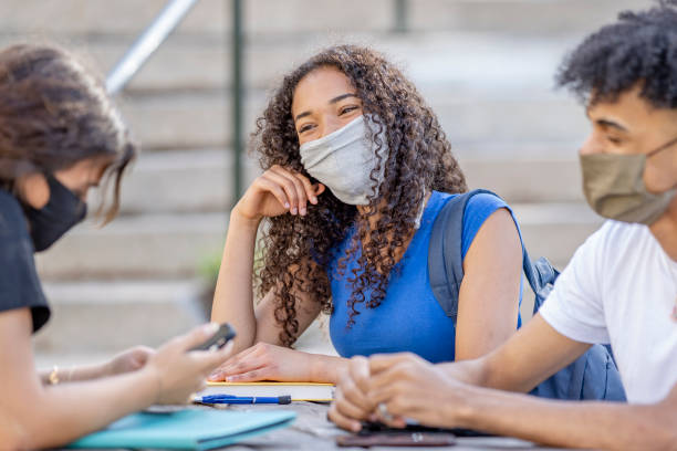 istock Students sitting on campus wearing protective face masks 1263065760