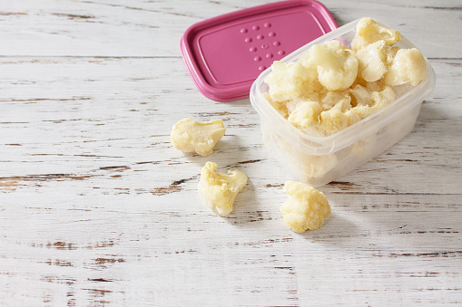 Healthy frozen food for the winter. Containers with frozen cauliflower. Copy space.