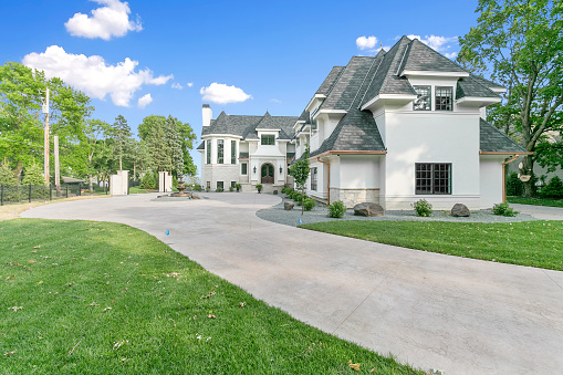 L-shaped mansion with long driveway leading to large opening by the house