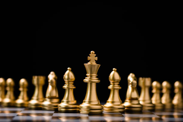 xadrez do rei dourado fica na frente de outras peças de xadrez. trabalho em equipe de liderança e estratégia de planejamento de estratégia de marketing. - chess defending chess piece chess board - fotografias e filmes do acervo