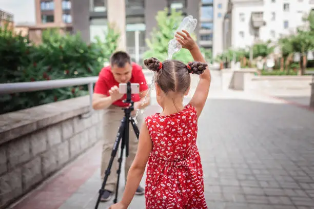 Photo of Make money online. Father recording film with daughter for family channel, video blogger