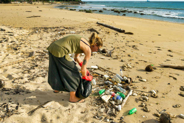 istock Plastic pollution beach cleanup one female 1263088056