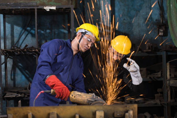 zwei mechaniker mit kreissägeschleifer im werk - industriearbeiter stock-fotos und bilder