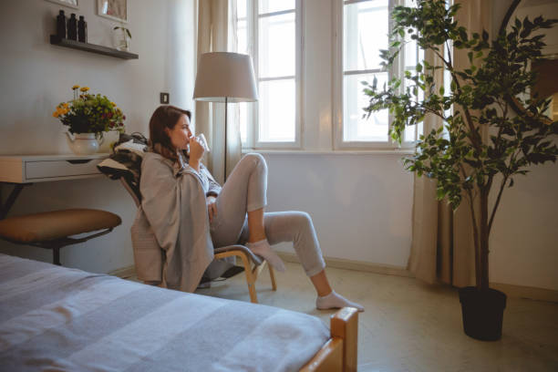 mujer en pijama disfrutando de su café de la mañana sentado en sillón - tea women beauty pampering fotografías e imágenes de stock