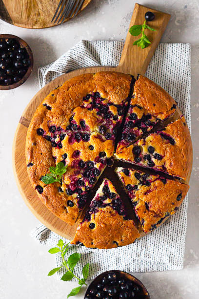 istock Sweet homemade cake or with cornmeal and black currant decorated with mint, selective focus. Light grey background. Summer baking. 1263095767