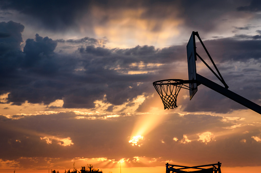 Sunrise behind a basketball court, the court located on the waterfront in Palermo, Sicily, Italy