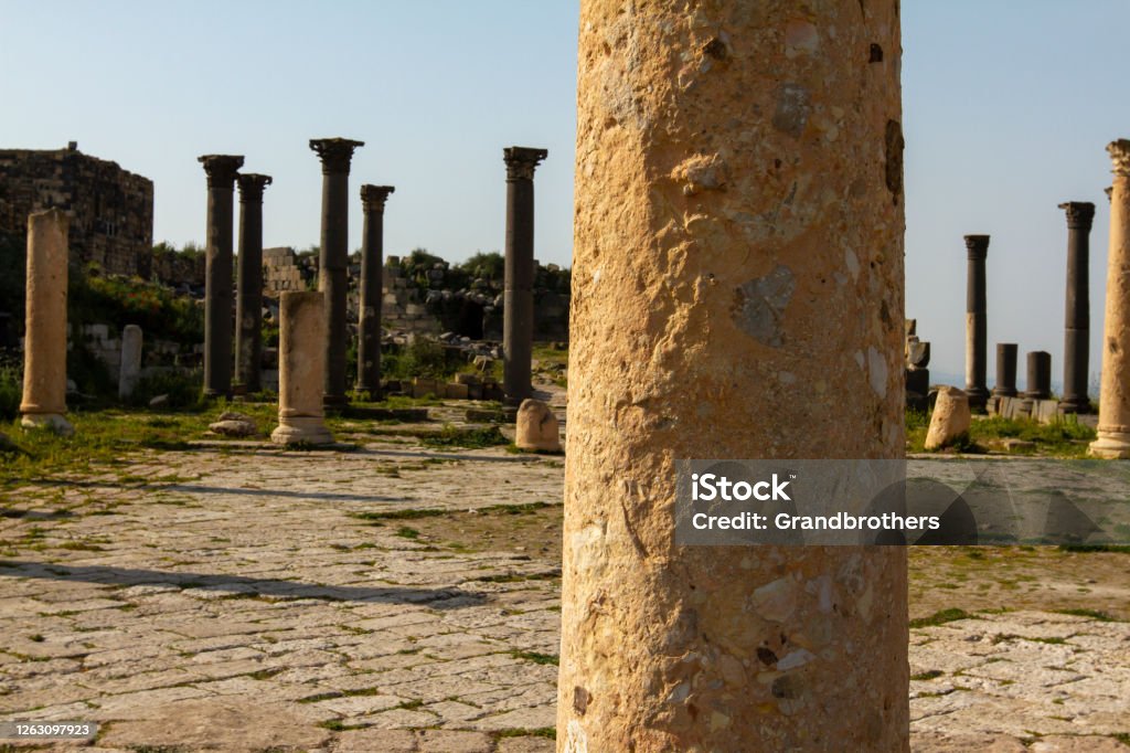 Ancient Roman Ruins (Umm Qais) Ancient ruins of Umm Qais, Jordan looking over Golan Heights at the cross section of Israel, Jordan and Syrian borders. Close up image showing the stone pillars in this historical landmark. All Middle Eastern Flags Stock Photo