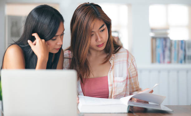 istock Young female university student reading book in library. 1263099413