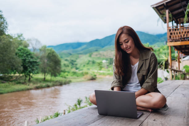 istock a beautiful asian woman working on laptop computer while sitting by the river with mountains and nature background 1263100141