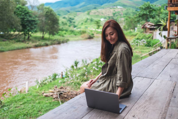 istock a beautiful asian woman working on laptop computer while sitting by the river with mountains and nature background 1263100157