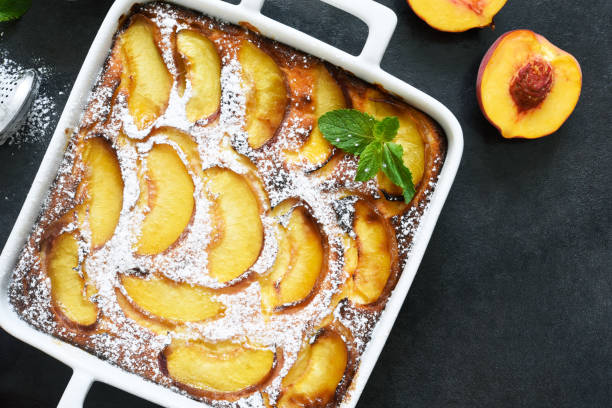 istock Delicate cake with peaches sprinkled with powdered sugar on a black concrete background 1263101483