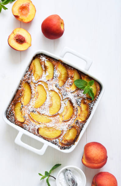 istock Delicate cake with peaches sprinkled with powdered sugar on a black concrete background 1263101490