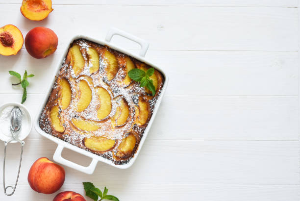 istock Delicate cake with peaches sprinkled with powdered sugar on a black concrete background 1263101497