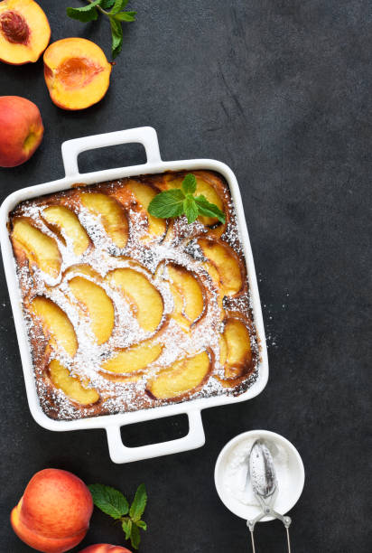 istock Delicate cake with peaches sprinkled with powdered sugar on a black concrete background 1263101507