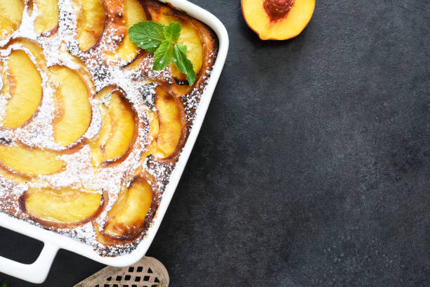 istock Delicate cake with peaches sprinkled with powdered sugar on a black concrete background 1263101515