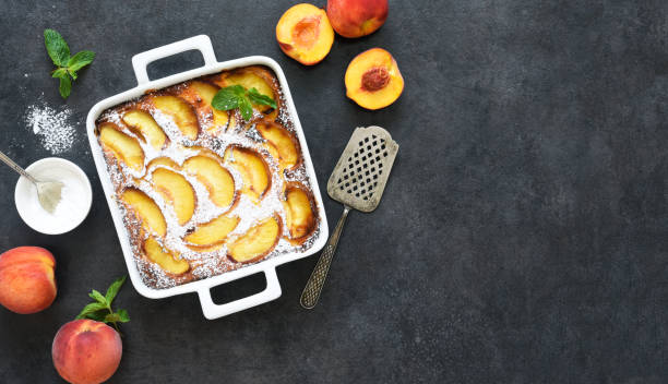 istock Delicate cake with peaches sprinkled with powdered sugar on a black concrete background 1263101539