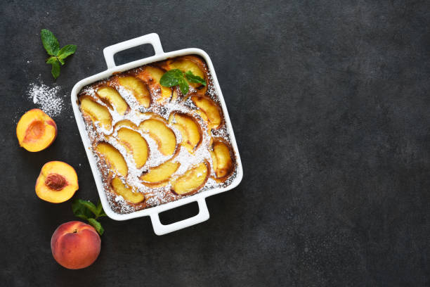 istock Delicate cake with peaches sprinkled with powdered sugar on a black concrete background 1263101564