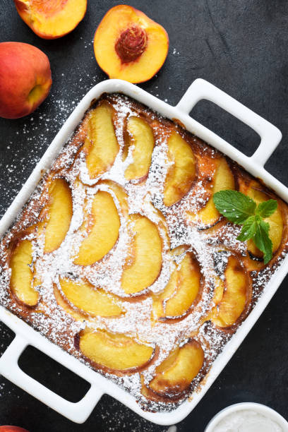 istock Delicate cake with peaches sprinkled with powdered sugar on a black concrete background 1263101612