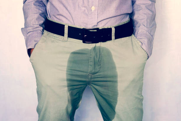 un homme restant dans le pantalon humide contre le mur. l’incontinence urinaire est une maladie de plus en plus populaire affectant les jeunes mâles. incontinence et pantalons mouillés. une tache sombre sur un pantalon clair. - enuresis photos et images de collection