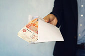 male hand on the envelope with one thousandth bills. concept of a bribe. blue background, selective focus
