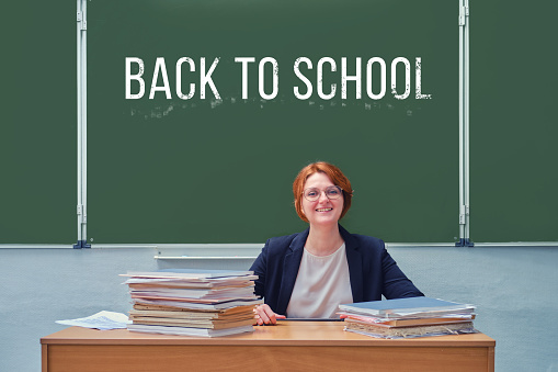 Woman teacher smiling on green blackboard background with the words \
