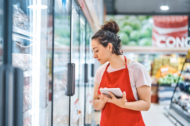 verkoopster in schort die bij supermarkt werkt - verkoopster stockfoto's en -beelden