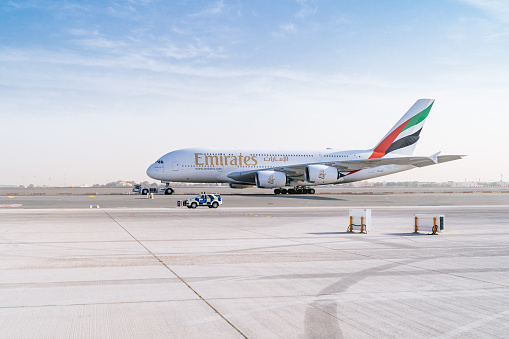 Morning in Dubai DXB airport. Airbus A380 aircraft of Emirates air company is being towed to the runway before a takeoff.