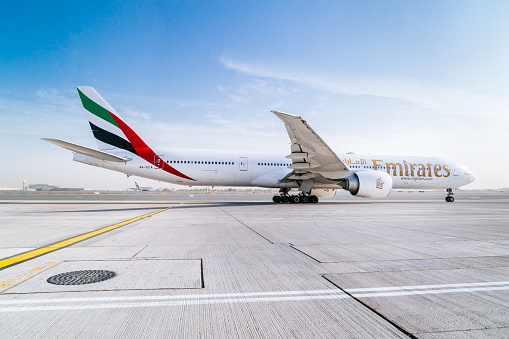 Morning in Dubai DXB airport. Boeing 777-300ER aircraft of Emirates air company is taxiing to a runway and preparing to takeoff.