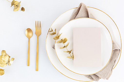 Festive christmas, wedding, birthday table setting with golden cutlery and porcelain plate. Blank card mockup. Restaurant menu template. Flat lay, top view