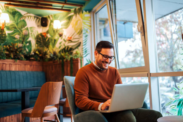 istock Smiling handsome man using laptop in cozy cafe. 1263104972