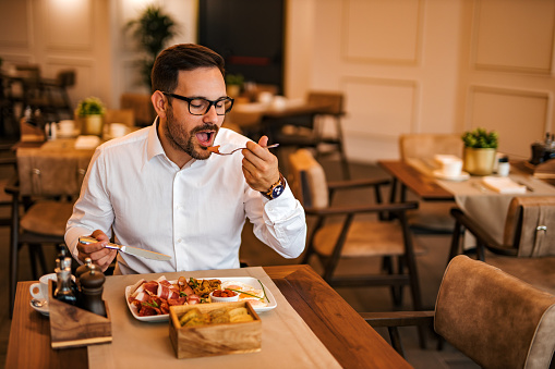 Successful man enjoying delicious meal at luxurious restaurant, portrait.