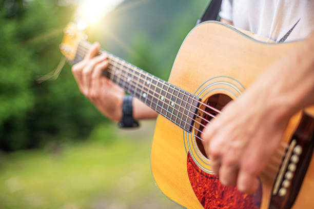 Acoustic Guitar Playing. Acoustic Guitar Playing. A man plays the guitar against the background of nature. guitarist stock pictures, royalty-free photos & images