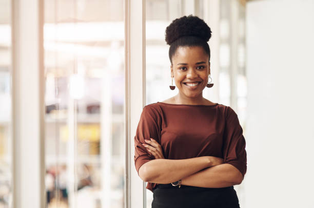 Confidence is key Cropped portrait of an attractive young businesswoman standing with her arms crossed in the office black business woman stock pictures, royalty-free photos & images