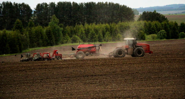 istock large tractor with plow plows  field before spring sowing of crops. tractor with  harrow drives across  plowed field and levels  arable land. 1263106571