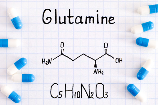 Chemical formula of Glutamine with some pills. Close-up.