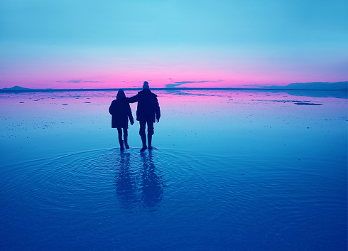Pop art styled silhouette of a couple enjoy walking on the flooding surface of Uyuni Salt Flats at sunset, Bolivia, South America, ( Self Portrait )