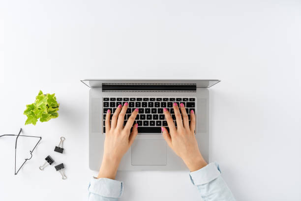 istock Woman’s hands working on laptop on white background with business accessories. Elegant office desktop. Top view 1263109489