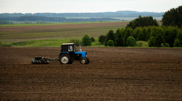 istock large tractor with plow plows  field before spring sowing of crops. tractor with  harrow drives across  plowed field and levels  arable land. 1263109902