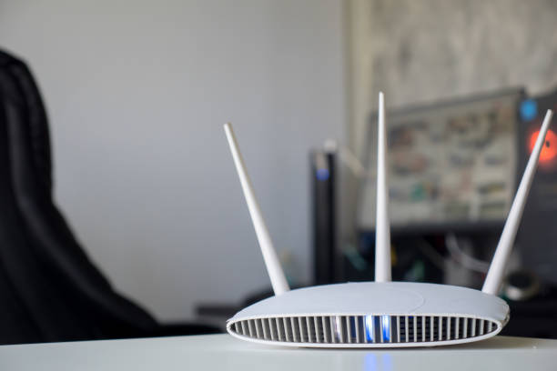 istock Close up of a wireless router on table at home with desktop computer background 1263109983