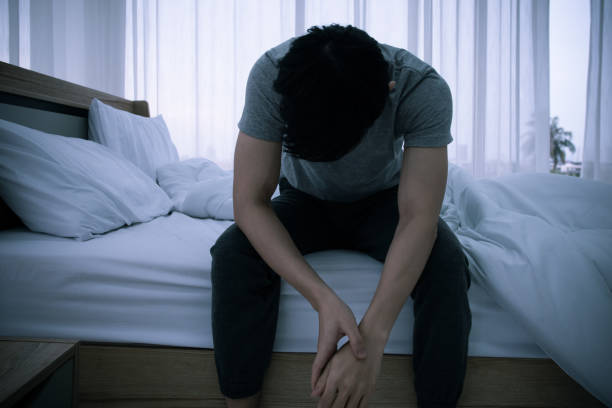 istock Stressed Asian young man sitting alone on bed. Bad relationship or bankrupt problem and sickness concept. 1263110064