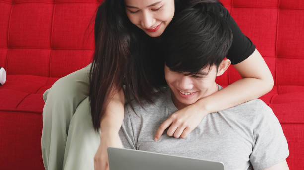 istock Happy Asian couple spending time together on sofa at home. 1263110622
