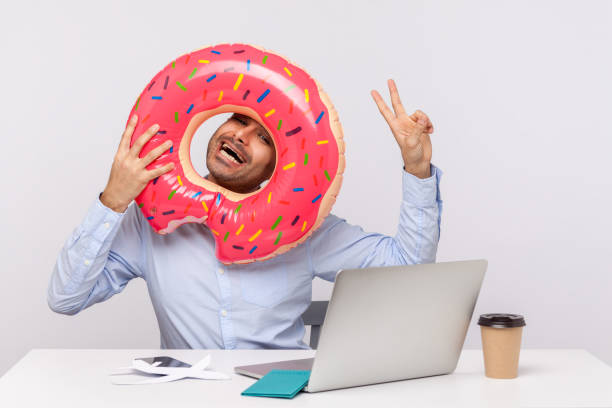 istock Extremely joyful man looking through rubber ring and showing victory gesture, sitting in office workplace with passport 1263111113